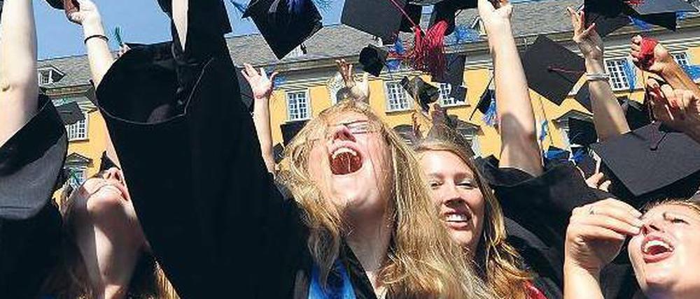 Absolventinnen der Uni Bonn werfen die Hüte ihrer Abschlusskostüme hoch.