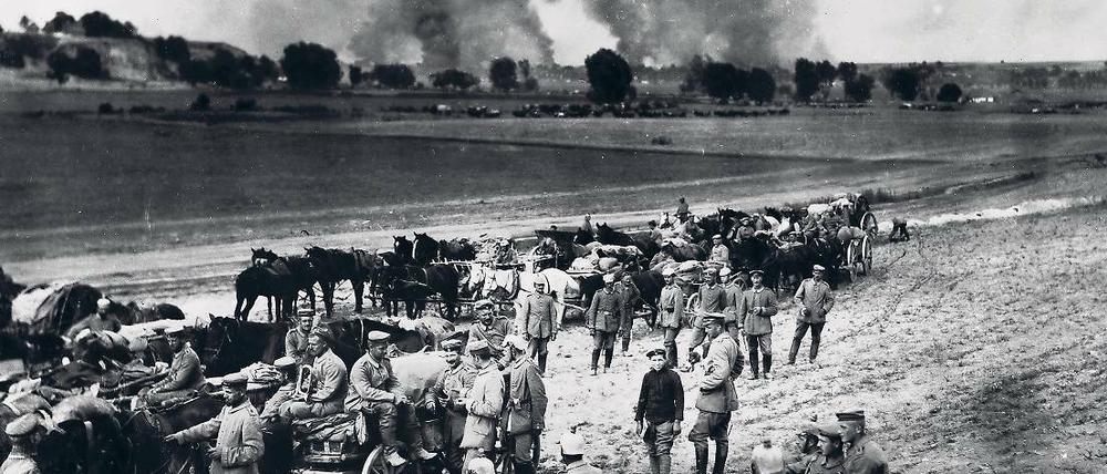 Deutsche Soldaten rasten im Jahr 1917 in Russland vor einem brennenden Dorf.
