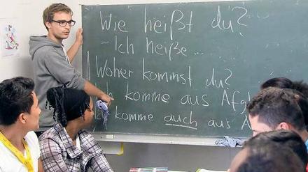 Ein studentischer Deutschlehrer steht an der Tafel, junge Männer und Frauen schauen auf Schriftzüge wie "Woher kommst du".