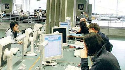 In einer Unibibliothek sitzen Studierende an Computern.