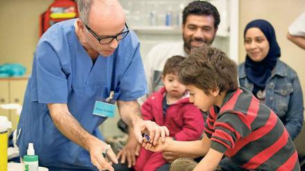 Ein Arztführt einen Kind beim Stempeln eines Impfausweises die Hand.