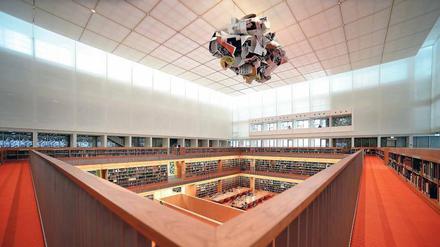 Über einem modernen Bibliotheksraum schwebt ein Kunstwerk, das an zusammengeknülltes Papier erinnert.