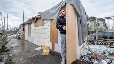 Ein junger Mann steht in der Tür einer selbstgezimmerten Hütte.