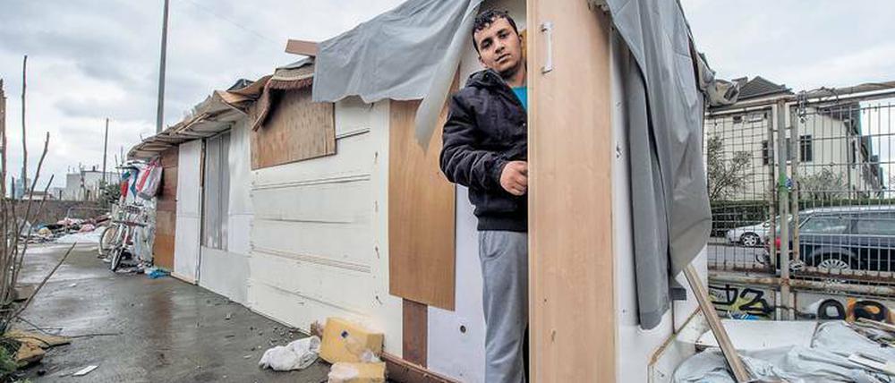 Ein junger Mann steht in der Tür einer selbstgezimmerten Hütte.