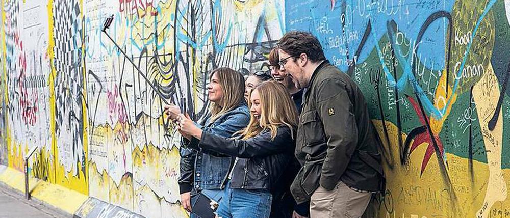 Bleibende Erinnerung. Touristen machen ein Selfie vor den Überbleibseln der Berliner Mauer. 