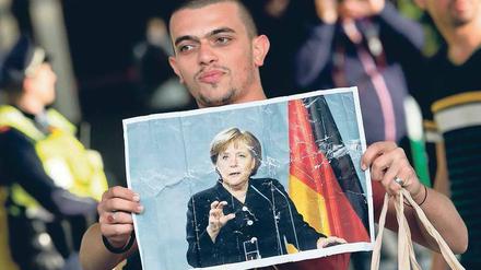 Ein junger Mann hält ein Foto der Bundeskanzlerin Angela Merkel hoch.