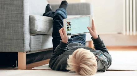 Ein Junge schaut Youtube-Filme auf einem Tablet-Computer.