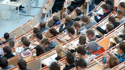 Studierende sitzen in einem Hörsaal und lauschen der Vorlesung eines Professors.