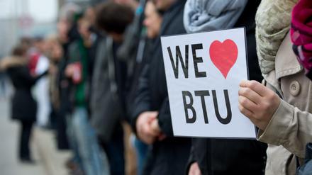 Eine junge Frau hält ein Schild mit der Aufschrift We love BTU in der Hand.