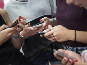 Ein Gruppe von Mädchen tippt auf ihren Smartphones herum.