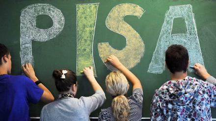 Vier Schüler malen zusammen den Schriftzug Pisa an eine Tafel.