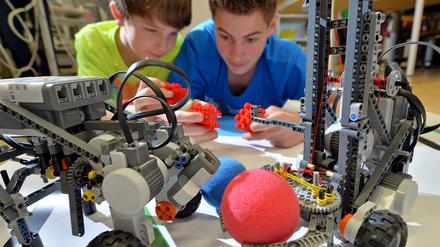 Zwei Schüler bauen an Roboter-Modellen.