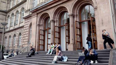 Studierende sitzen auf den Treppenstufen vor einem Eingang der Universität in Aachen.