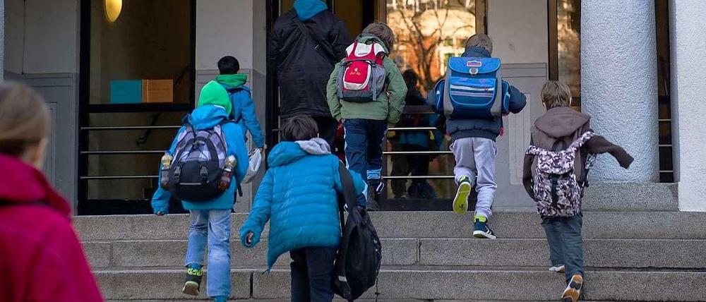 Grundschüler steigen die Treppe zum Eingang ihrer Schule hoch.