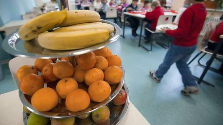Eine Etagere mit verschiedenen Obstsorten steht auf einem Tisch in der Mensa einer Schule.