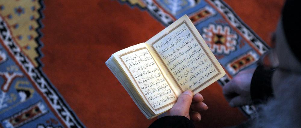 Ein Mann hält einen Koran in der Hand.