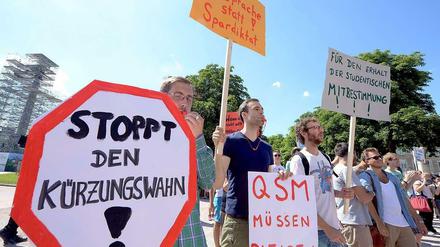 Studierende stehen in Stuttgart vor einem Uni-Gebäude und halten Transparente mit der Aufschrift "Stoppt den Kürzungswahn" hoch.