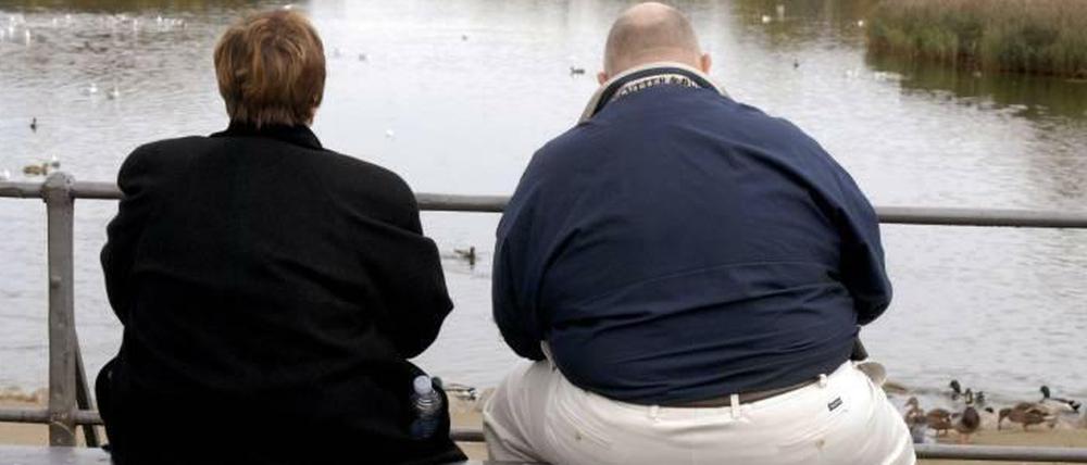 Zwei Übergewichtige sitzen auf einer Bank
