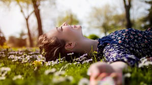 Ein junge Frau liegt entspannt auf der Wiese (Symbolbild).