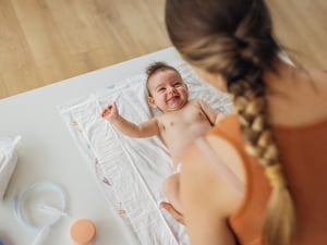 Ein Baby liegt auf einem Tuch und schaut seine Mutter an.