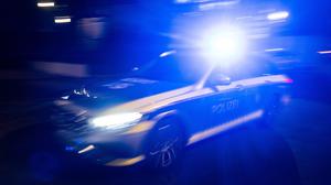 Ein Polizeifahrzeug fährt mit Blaulicht an einem Gebäude vorbei. (Symbolbild)