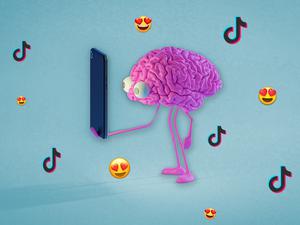 Ein comichaftes Gehirn mit großen Glubschaugen starrt in einen Handybildschirm, während um es herum Herzaugen-Emojis und Logos von Tiktok fliegen. 