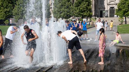 Personen kühlen sich an einem heißen Sommertag am Springbrunnen im Lustgarten auf der Museumsinsel im Bezirk Mitte ab. 