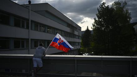 Slowakei, Banska Bystrica: Ein Mann schwenkt die slowakische Nationalflagge vor dem F. D. Roosevelt Universitätskrankenhaus, in dem der angeschossene und verwundete slowakische Premierminister Fico behandelt wird.
