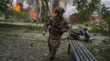 Ein Polizist läuft vor einem brennenden Haus in Wowtschansk, das durch einen russischen Luftangriff zerstört wurde. 