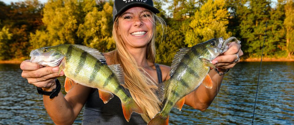 Influencerin Babs Kijewski mit zwei Barschen, ihren Lieblingsfischen, die sie an einem Baggersee gefangen hat.