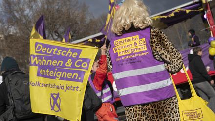 Mit einer Fahne und einer Weste des Bündnisses „Deutsche Wohnen und Co enteignen“ steht ein Teilnehmer an der Demonstration „Karneval der Enteignung“ in Kreuzberg auf dem Oranienplatz. 