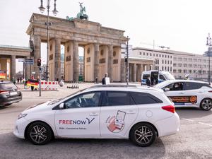 Ein Auto mit Werbung von Freenow vor dem Brandenburger Tor.