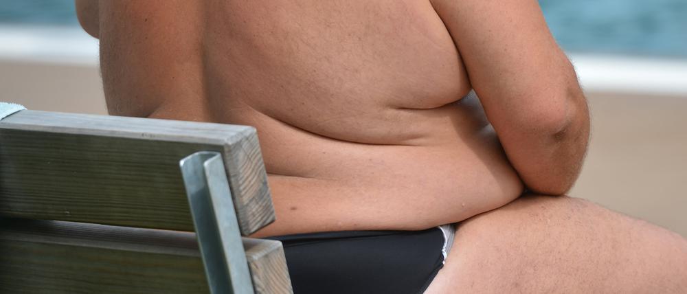Ein übergewichtiger Mensch sitzt in einem Freibad in Stuttgart.