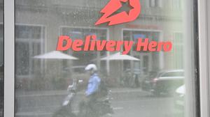 Ein Mopedfahrer spiegelt sich in einer Glasscheibe an der Zentrale des Essenlieferdienstes Delivery Hero.
