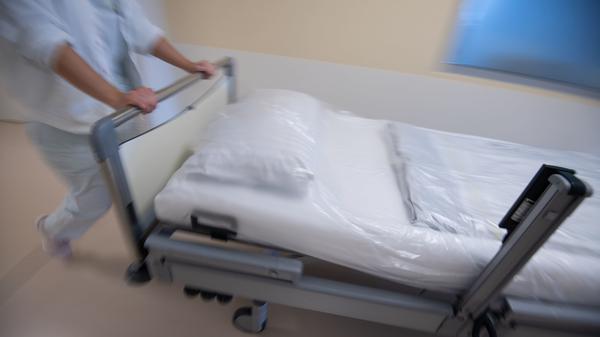 Eine Krankenpflegerin schiebt ein Krankenbett durch einen Gang einer Station (Symbolbild).