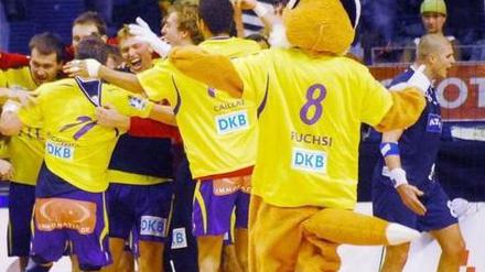 Maskottchen Fuchsi jubelt mit den Handballern der Reinickendorfer Füchse.