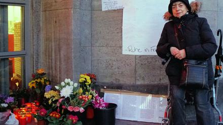 Anwohnerin Stenia Getsch steht vor Blumen, Grablichtern und einem Kondolenzplakat für den verstorbenen Obdachlosenzeitungs-Verkäufer Jürgen Zietz.