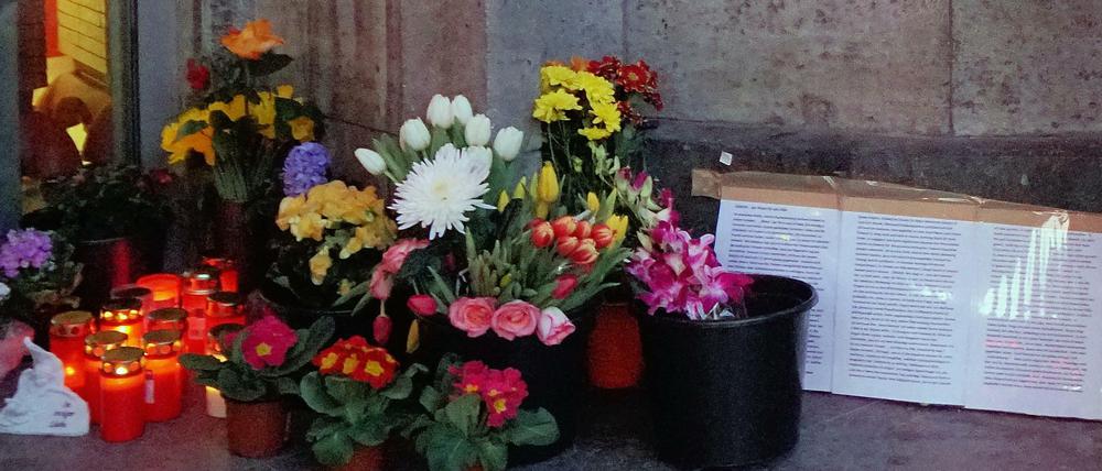 Anwohnerin Stenia Getsch steht vor Blumen, Grablichtern und einem Kondolenzplakat für den verstorbenen Obdachlosenzeitungs-Verkäufer Jürgen Zietz.