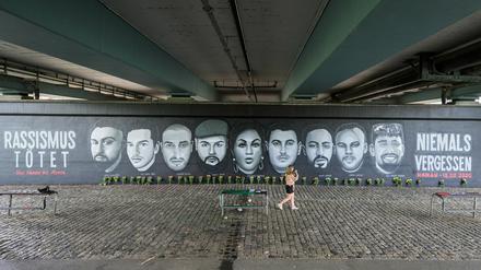 Eine Frau geht vor den Porträts von Opfern des Anschlags von Hanau entlang, die unter die Frankfurter Friedensbrücke gemalt wurden.  