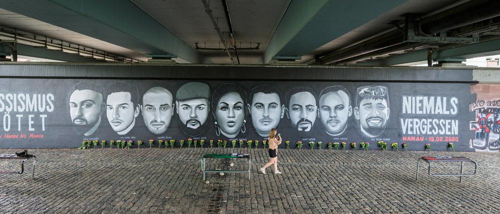 Eine Frau geht vor den Porträts von Opfern des Anschlags von Hanau entlang, die unter die Frankfurter Friedensbrücke gemalt wurden.  