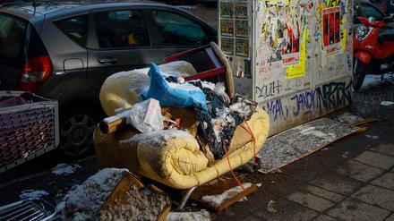 Ein alter Sessel und diverser Müll auf einem Gehweg in Berlin-Neukölln.