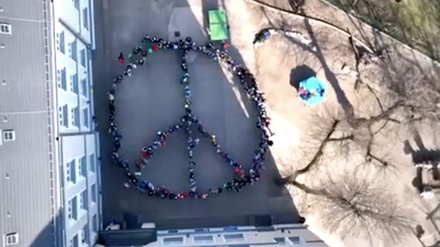 Schüler:innen formieren sich zu Peace-Zeichen, Screenshot aus einem aus der Luft gefilmten Video.