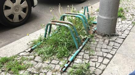 Verrosteter, grün gefärbter, altmodischer Fahrradständer am Straßenrand in Berlin-Wilmersdorf.