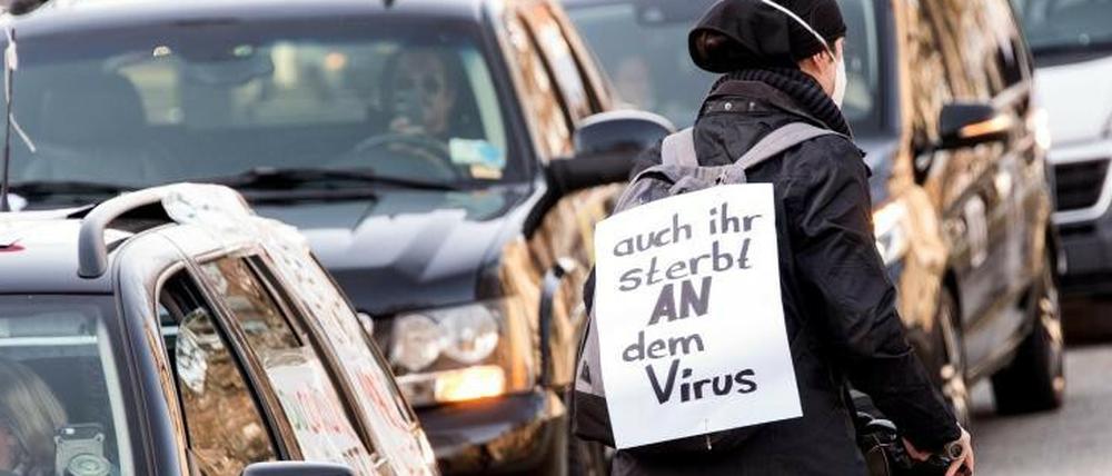 Radfahrerin protestiert mit Transparent ("Auch ihr sterbt an dem Virus") gegen Querdenker-Autokorso.