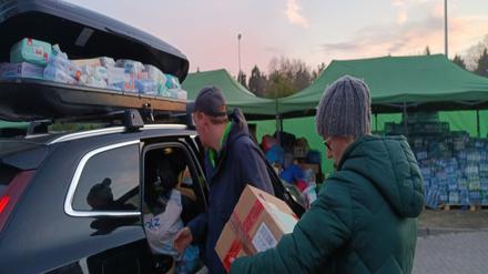 Helferinnen und Helfer entladen ein Auto mit Hilfsgütern für Geflüchtete an der polnisch-ukrainischen Grenze.