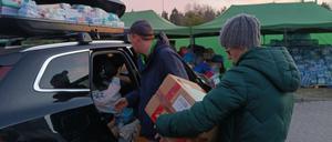 Helferinnen und Helfer entladen ein Auto mit Hilfsgütern für Geflüchtete an der polnisch-ukrainischen Grenze.