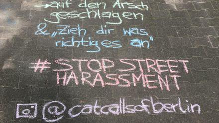 Kreideschriftzug auf der Straße, der sexuelle Belästigung beschreibt ("auf den Arsch geschlagen").