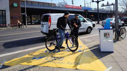 Vorsicht, Toter Winkel! Die Polizistin am S-Bahnhof Tiergarten erklärt einem Radler anhand der gelben Plane, welchen Bereich viele Lkw-Fahrer beim Rechtsabbiegen nicht sehen.