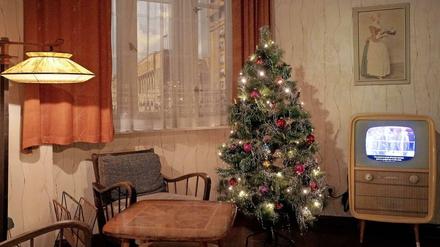 Aluminium-Lametta glitzert. Weihnachtsatmosphäre im DDR-Musterzimmer der "Story of Berlin". Über dem Schwarz-Weiß-Fernseher hängt ein Bild des Scholadenmädchens.