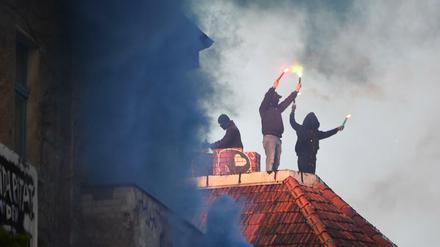 Unterstützer der linksradikalen «Revolutionären 1. Mai-Demonstration» in 2019 stehen mit Pyrotechnik in den Händen auf einem Dach in Friedrichshain.